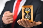Man in a suit with tie holding an hourglass