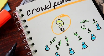 Notebook with crowd funding sign on a table.