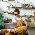 Young woman using laptop in a small gardening shop