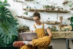 Young woman using laptop in a small gardening shop