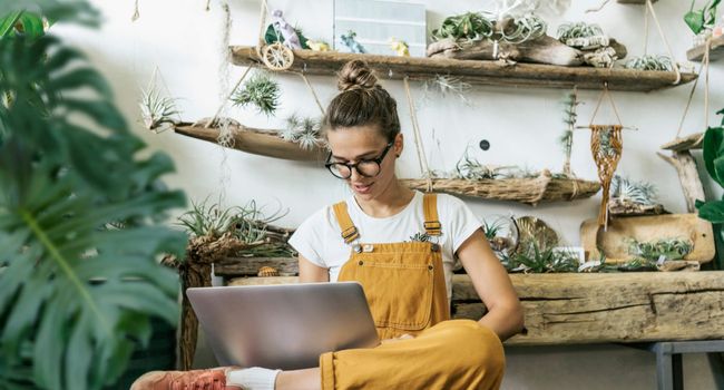 Young woman using laptop in a small gardening shop